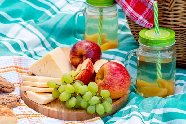 Picnic on the grass on a summer day - basket, grapes, cheese, bread, apples - a concept of summer outdoor recreation