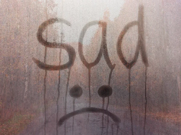 Escrito por triste e Emoji em vidro enevoado contra o pano de fundo da paisagem de outono. Outono, saudade, solidão, conceito de problemas — Fotografia de Stock