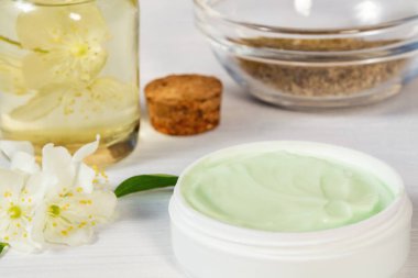 Krem kavanoz doğal bitki maddeler, yağlar ve otlar, beyaz ahşap arka plan üzerinde yasemin çiçekleri yapılan - organik kozmetik kavramı nın hazırlanması, yakın