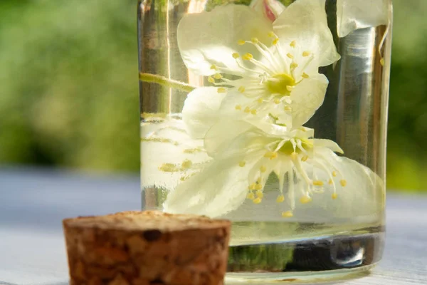 Flores de philadelphus en algún lugar llamado jazmín o naranja simulada y una botella de aceite en una mesa de madera blanca, de cerca — Foto de Stock