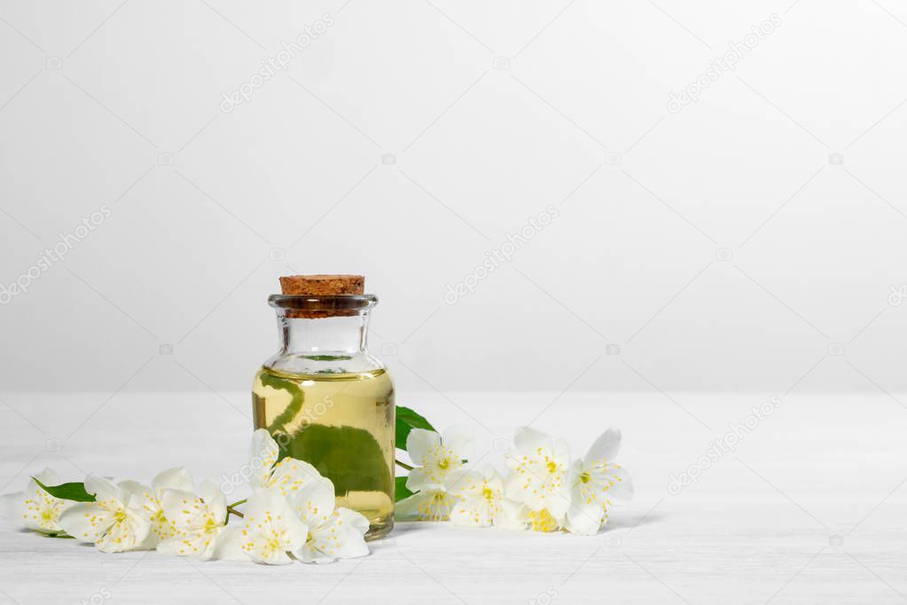 flowers of philadelphus somewhere called jasmine or mock orange and a bottle of oil on a white wooden table