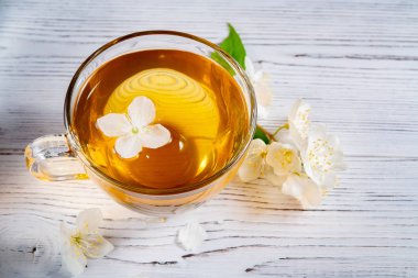 Philadelphus çiçekleri bir yerde yasemin veya sahte portakal ve Fincan beyaz bir ahşap masada kokulu yasemin çayı ile denir