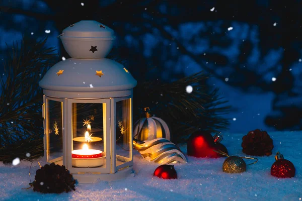 Lanterna com uma vela acesa e decorações de Natal em uma mesa coberta de neve — Fotografia de Stock