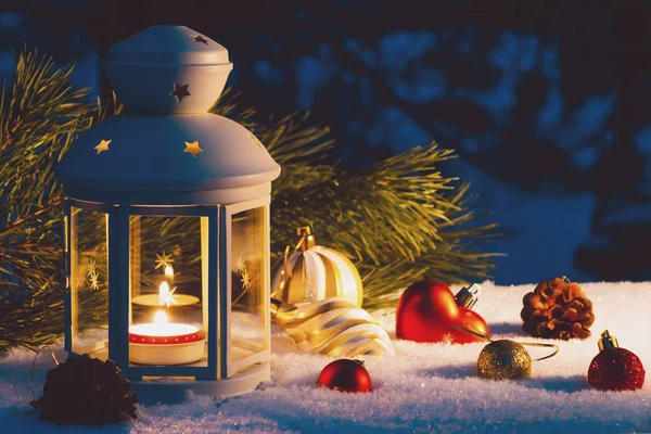 Lanterna con candela accesa e decorazioni natalizie su un tavolo innevato — Foto Stock