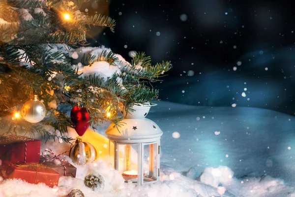 Composición navideña: regalos y una linterna en la nieve bajo un árbol de Navidad decorado con luces y decoraciones de árboles de Navidad, espacio para copiar, lugar para texto —  Fotos de Stock