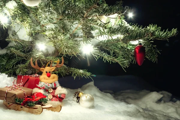 Composição de Natal - Árvore de Natal na neve, presentes, veados de brinquedo e a inscrição Feliz Natal e Feliz Ano Novo, espaço de cópia, lugar para texto — Fotografia de Stock