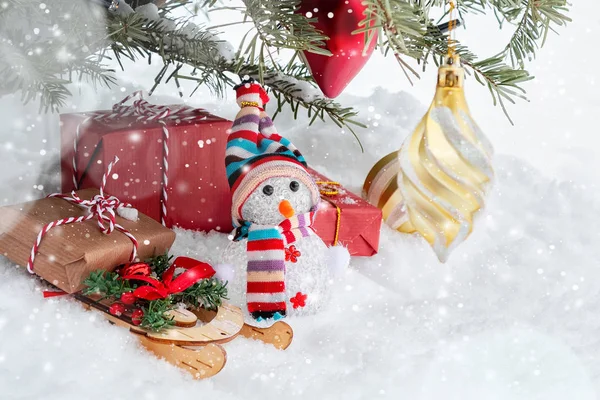 Composição de Natal abaixo da árvore de Natal - um boneco de neve, caixas com presentes em um trenó e outras decorações, lugar do texto, espaço de cópia — Fotografia de Stock