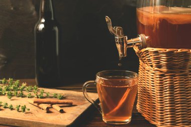 Taze ev yapımı Kombucha manyetasyonlu çay içeceği kavanozda musluk ve siyah arka plan üzerinde fincan ve şişe