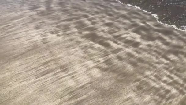 Tournage vidéo en mouvement de sable doré sur une plage océanique et vagues au coucher du soleil — Video