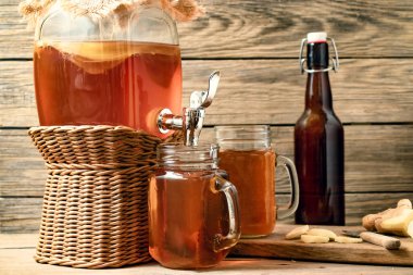 Taze ev yapımı Kombucha musluk ve ahşap arka plan üzerinde konserve kupaları ile kavanozda çay içeceği fermente