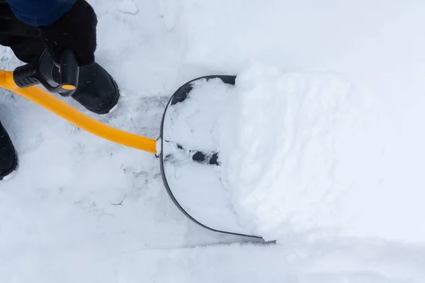Un uomo pulisce la neve nel cortile con una pala dopo una forte nevicata — Foto Stock