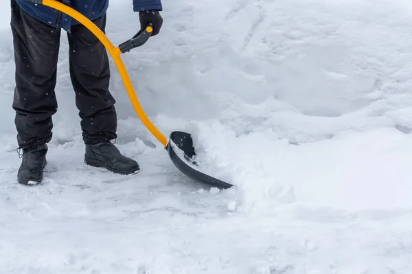A man cleans snow in the yard with a shovel after a heavy snowfall — Stock Photo, Image