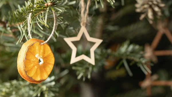 Concept de Noël zéro déchet. Arbre de Noël décoré d'ornements faits de matériaux naturels - une tranche de figures séchées d'orange et de bois, gros plan — Photo