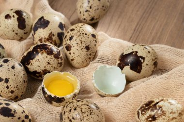 Dekoratif kumaş üzerine birkaç bıldırcın yumurtası. Ahşap bir masa, yakın plan, düz yatak.