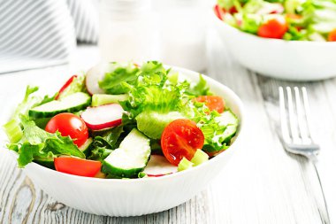 Beyaz ahşap arka plan üzerinde beyaz seramik kase vitamin salatası