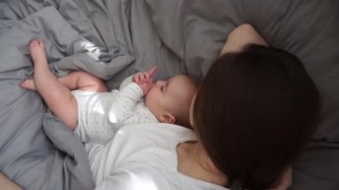 Küçük bir bebek sabah annesiyle yatıyor.