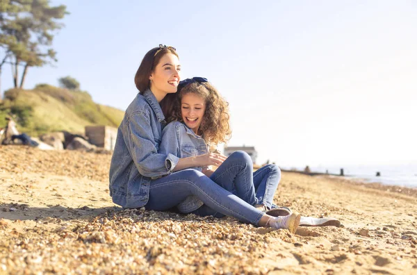 Mother and daughter sitting at the beach, enjoying their time together