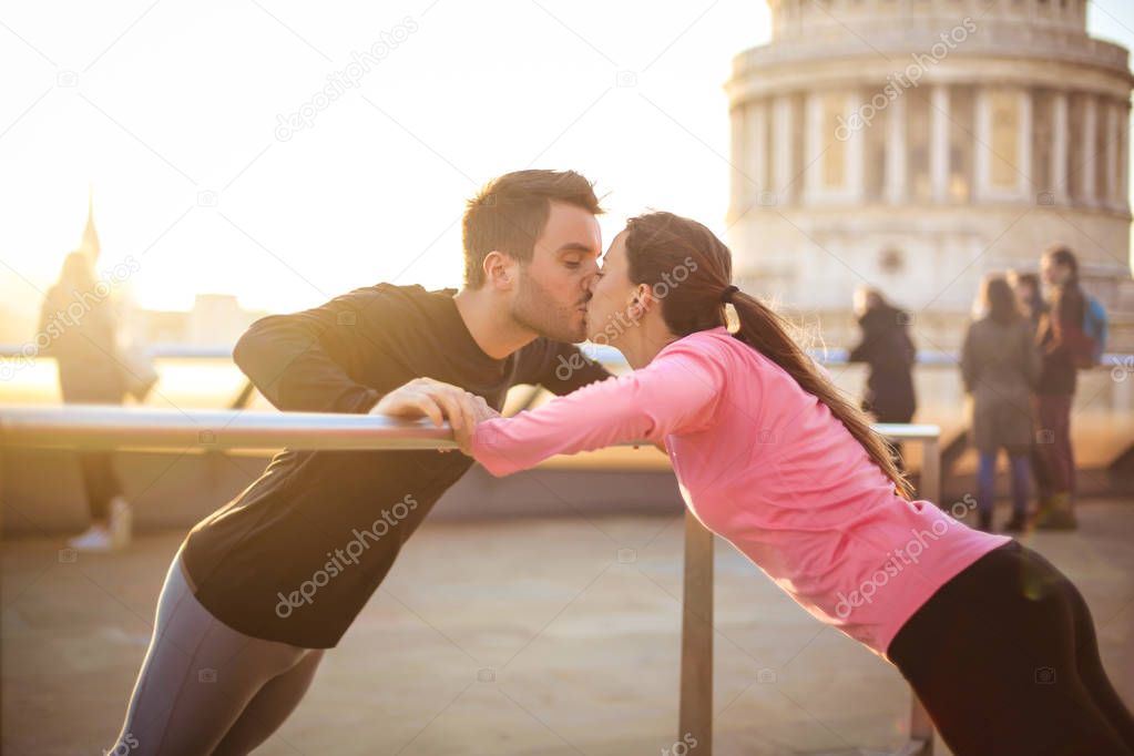 Romantic sportive couple kissing while doing push ups
