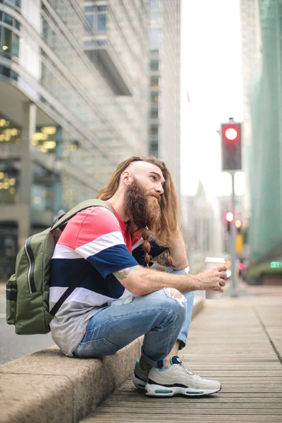 Handsome guy sitting in the street, drinking a coffee