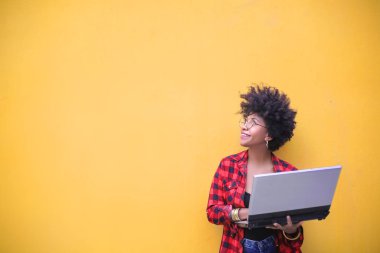 Kıvırcık saçlı güzel afro-amerikan kız dizüstü bilgisayar tutan
