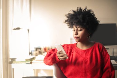 Akıllı telefon kullanarak kıvırcık saçlı güzel afro-amerikan kız