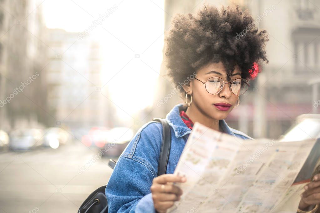 Beautiful tourist girl with curly hair holding map