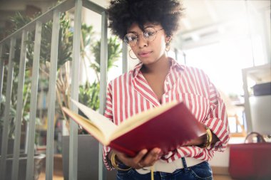 Kıvırcık saçlı güzel afro-amerikan kız kitap tutan