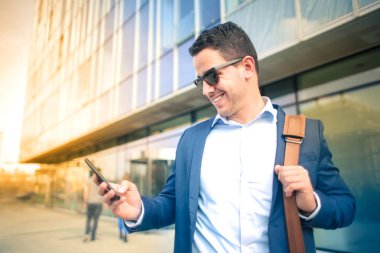 Sokakta akıllı telefon kullanan yakışıklı bir genç.
