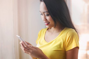 Genç esmer kadın akıllı telefon kullanıyor.