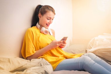 Evde akıllı telefon kullanan güzel bir kız.