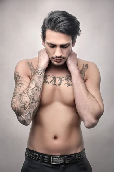 Handsome young shirtless man with tattoos