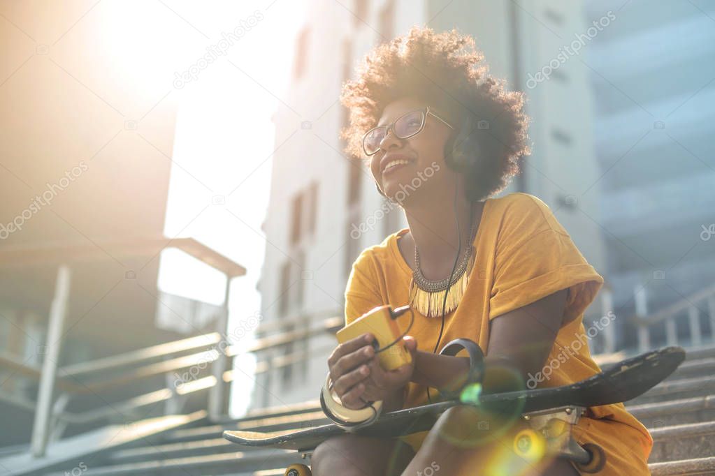 Beautiful cheerful girl listening music in the street