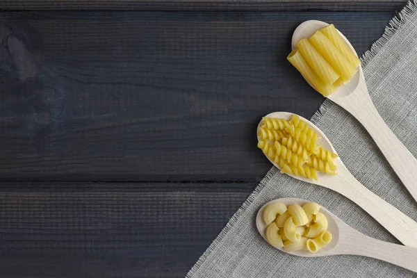 Uncooked pasta in a wooden spoon — Stock Photo, Image
