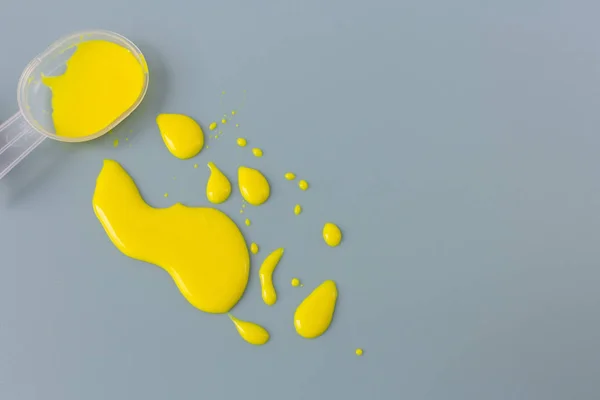 Liquid yellow medicine mixture on measuring spoon on a blue back