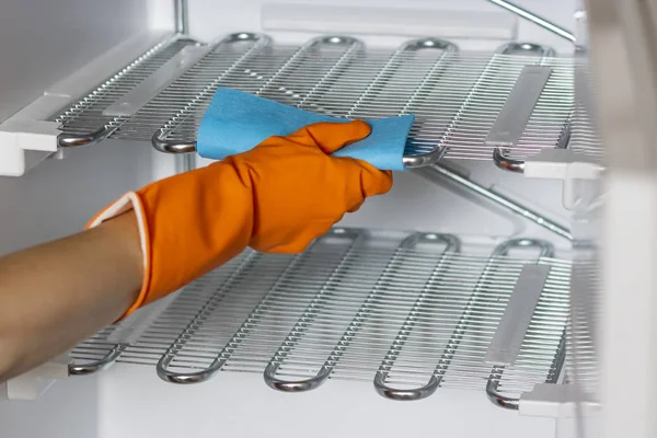 La mano femenina con guantes protectores está limpiando el refrigerador dentro. — Foto de Stock