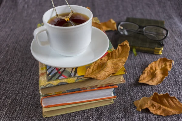 Cup of fragrant hot tea among yellow leaves on a plaid.