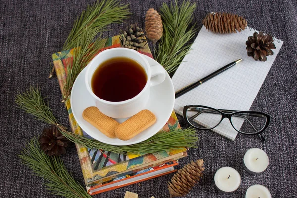 Cup of fragrant hot tea among Christmas tree branches and pine c