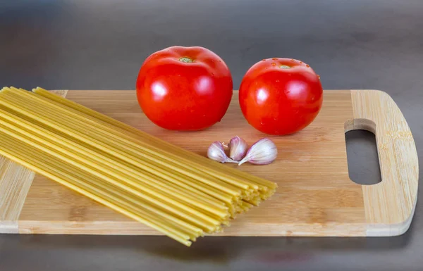 Massa de espaguete de trigo integral não cozida com tomates em uma redução — Fotografia de Stock