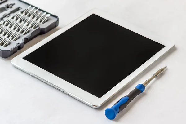 Tablet PC con pantalla y herramientas vacías, destornillador en una ba blanca — Foto de Stock