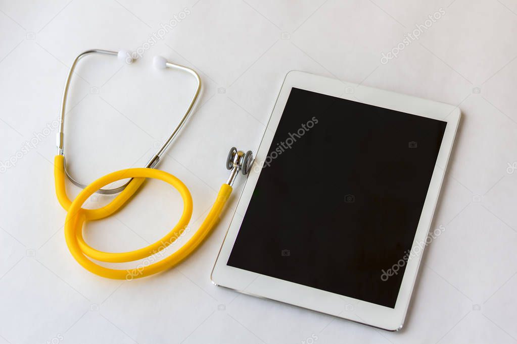 Tablet PC and stethoscope on a white background close up.