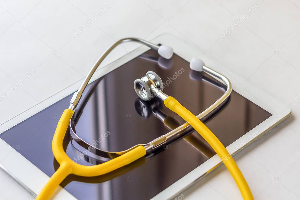Tablet PC and stethoscope on a white background close up.