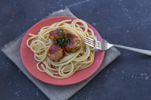 Espaguete com almôndegas e molho de tomate em uma placa vermelha — Fotografia de Stock