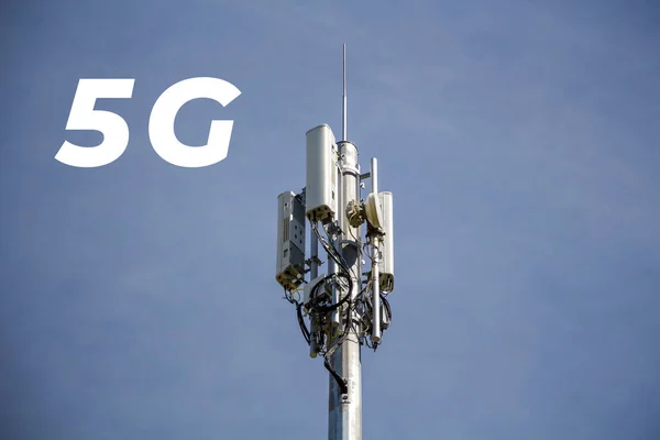 Inscription 5G and telecommunication, cellular tower and antenna. Radio tower with 4G, 5G network against blue sky