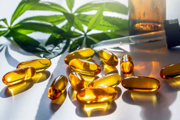 Medical cannabis products: leaf, capsules and CBD oil on white background. Pharmaceutical gelatin softgels with biological plant herbal. Organic dietary supplements concept