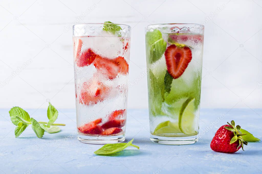 Two glass of refreshing cool detox drink with strawberry, lime and mint on blue background. Various summer lemonades or ice tea. Mojito cocktail with ice cubes. Healthy eating. copy space for text      