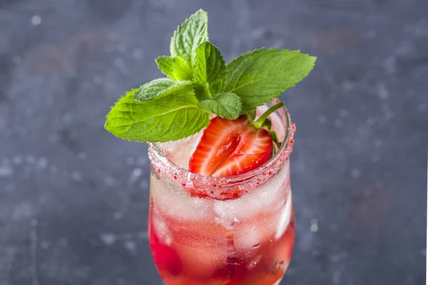 Cooling Rossini italian alcoholic cocktail with sparkling wine, strawberry, ice cubes in champagne glass. Refreshing summer lemonade or ice tea decorated with mint leaves