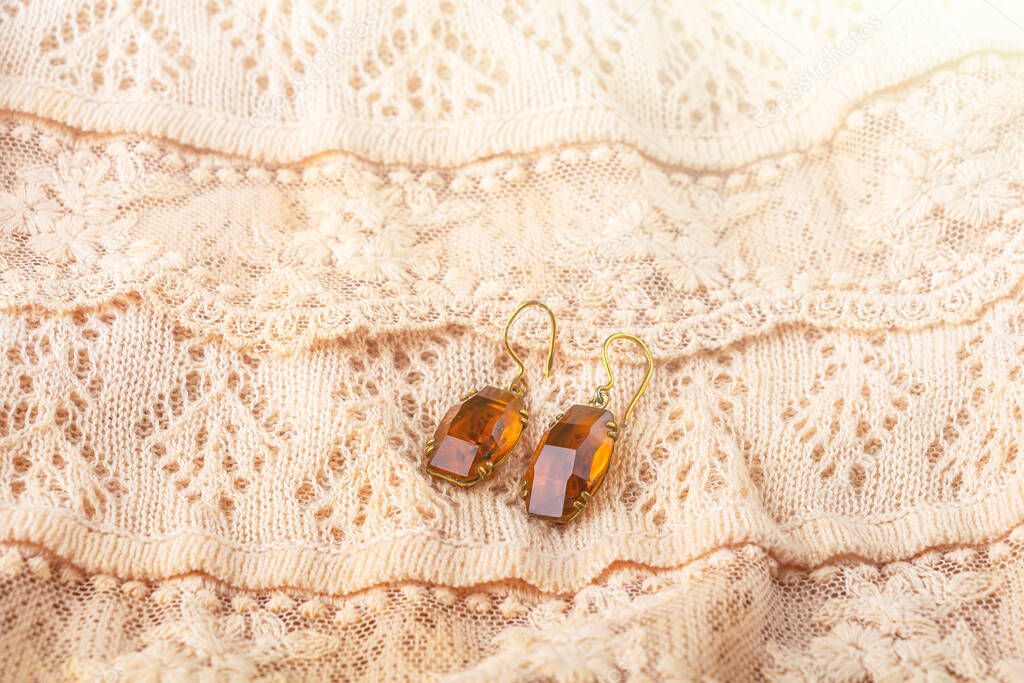 Vintage antique earrings, eardrop from citrine on  delicate ivory-colored lace cloth. Oldfashioned decoration from grandma's jewelry box. Wedding concept. 