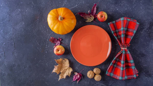 Autumn harvest festival and thanksgiving day table setting. Fallen leaves, pumpkin, apples, nuts, empty plate and checkered napkin. Thanksgiving rustic still life, mock up, banner