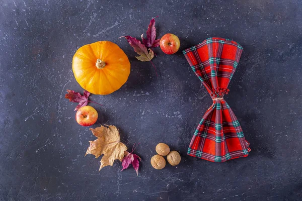 Autumn harvest festival and thanksgiving day table setting. Frame from fallen leaves, pumpkin, nuts and checkered napkin. Thanksgiving rustic still life, mock up