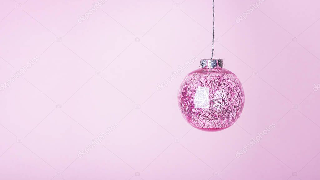 Christmas composition. Christmas pink bauble, shiny ball hanging on pastel background. Mock up for new year gretting card. Close up, copy space for text or lettering, banne